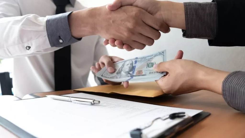 Business men having a handshake, exchanging money.